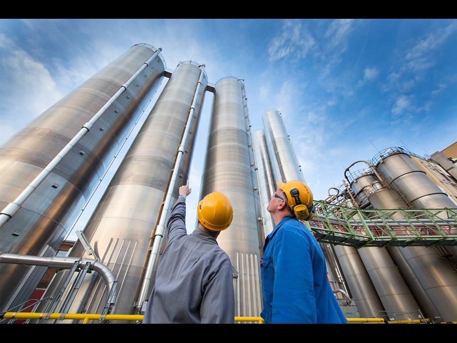 Employees working and pointing towards the pipes of a Covestro site.