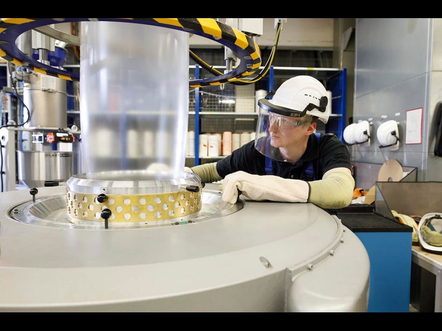 Employee with protective clothing is inspecting a machine.