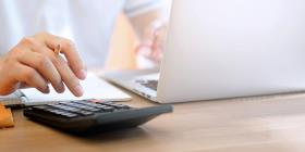Person working with a laptop and a calculator
