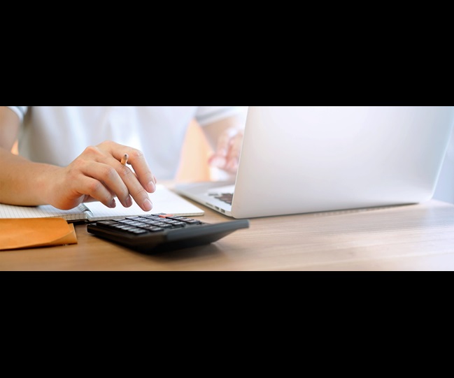 Person working with a laptop and a calculator