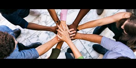Group of people lined up in a circle and put their hands on top of each other.