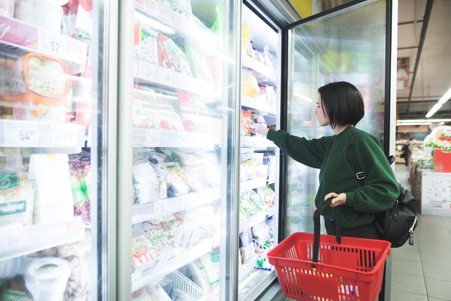 A woman reaching for products in a refrigirator of a supermarket