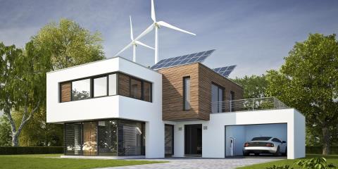 Modern residential building with solar roof and wind turbines in the background.