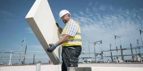 Worker in protective clothing wearing an insulation panel.