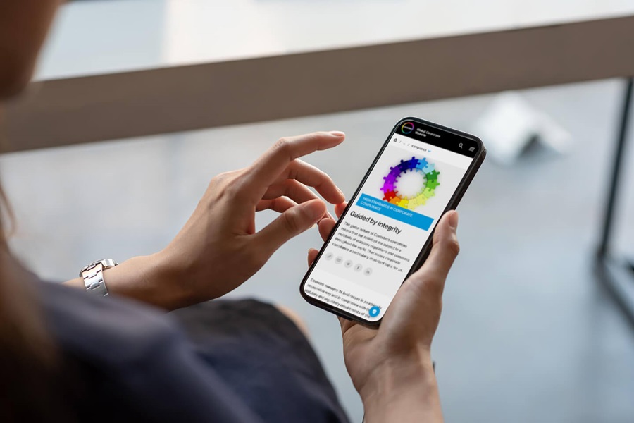 Person holding smartphone displaying colorful circular diagram and 'Guided by Integrity' text on screen