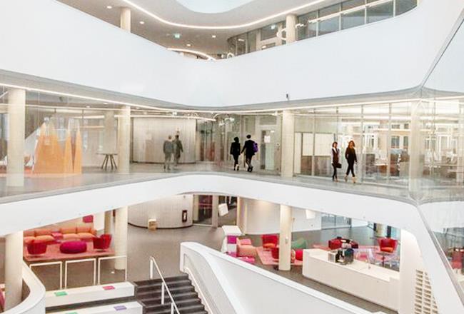 People walking in a modern building with glass walls.